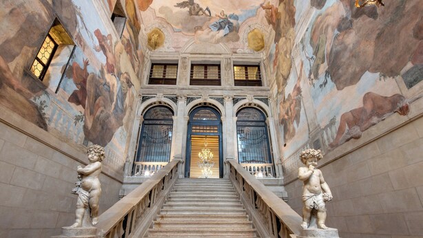 A grand staircase with ornate balustrades, leading to a door with a golden frame. - Ca' Sagredo (Venice)