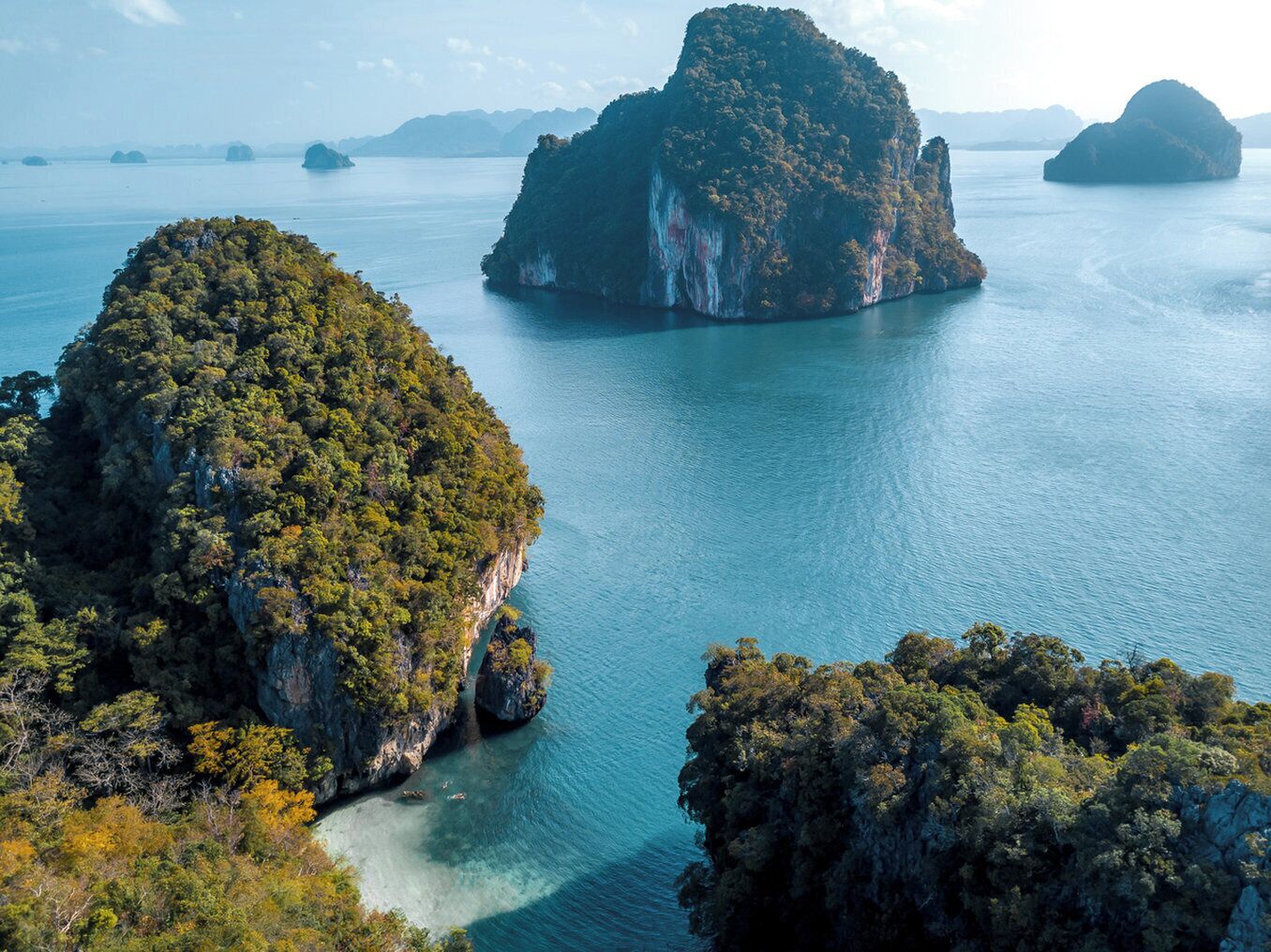 A coastal landscape with large rock formations and clear blue waters.