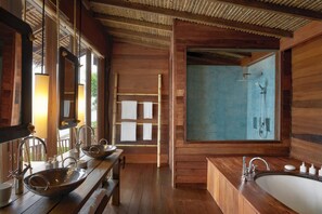 A wooden bathroom with a large sink, a bathtub, and a shower.