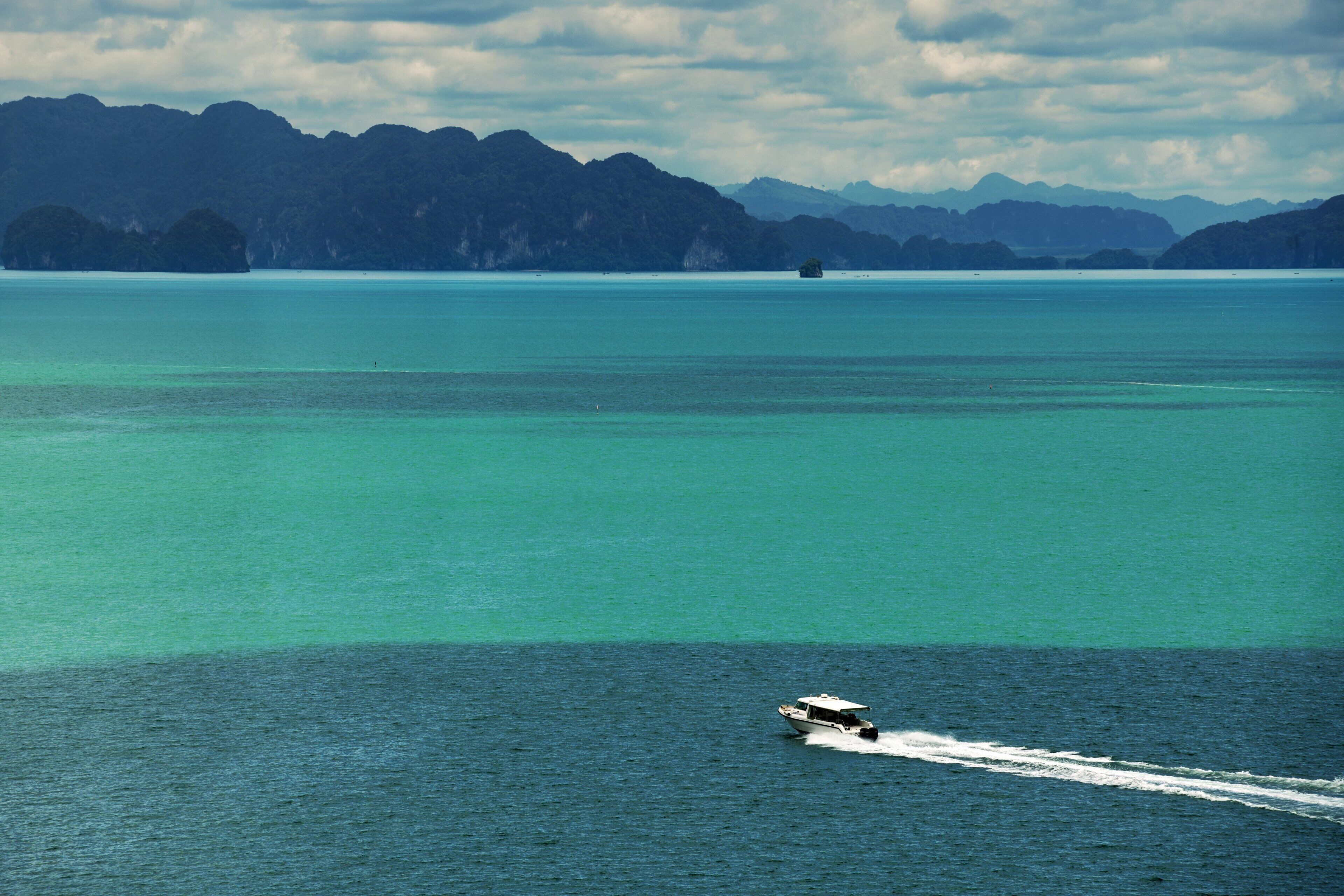 A boat on a calm sea with mountains in the background.