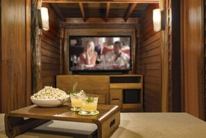 A cozy room with wooden walls, a television, a bowl of popcorn, and two drinks on a table.