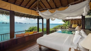 Un dormitorio con una cama grande, vistas al mar y una zona de piscina.