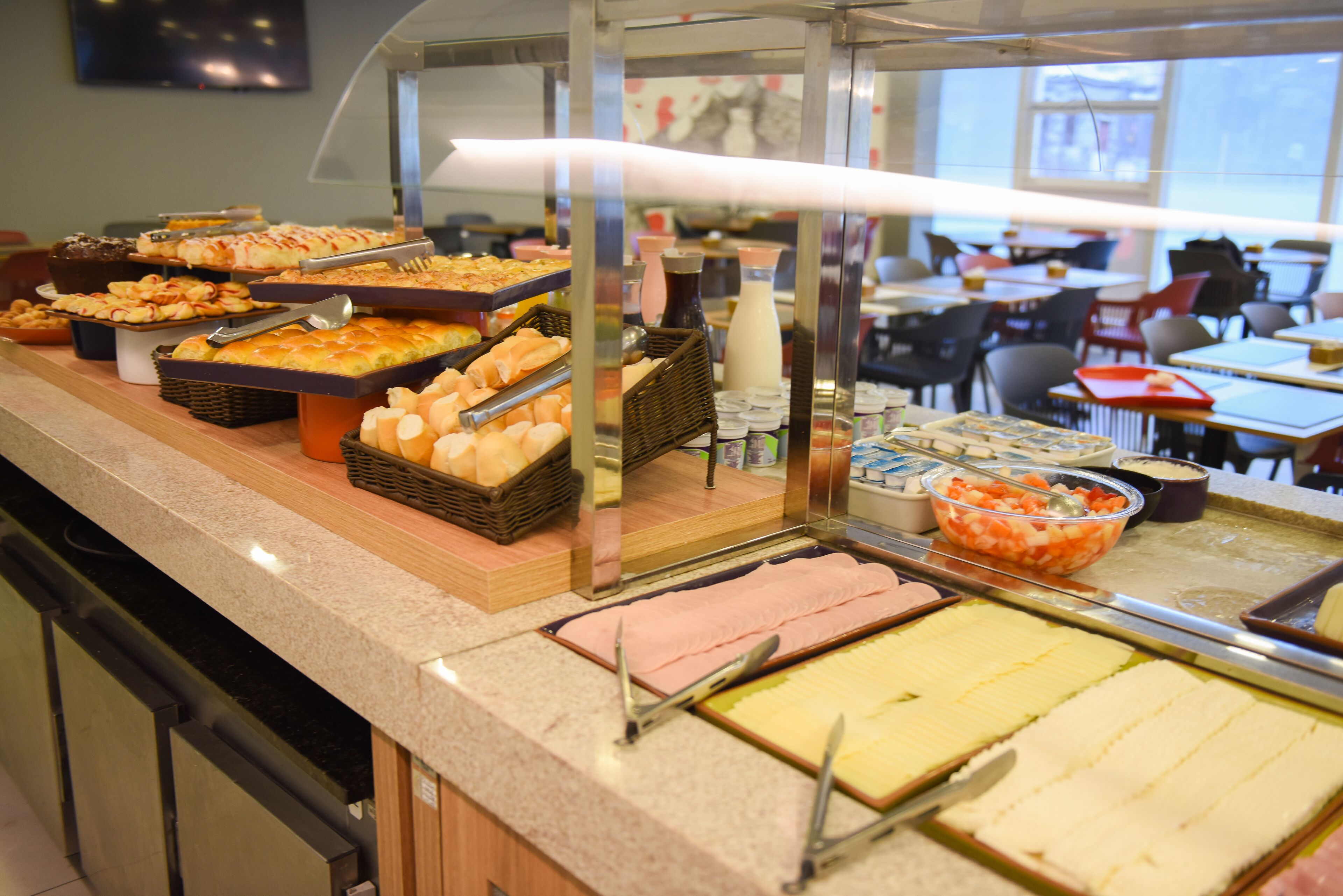 Buffet com diversos alimentos e uma divisória de vidro.