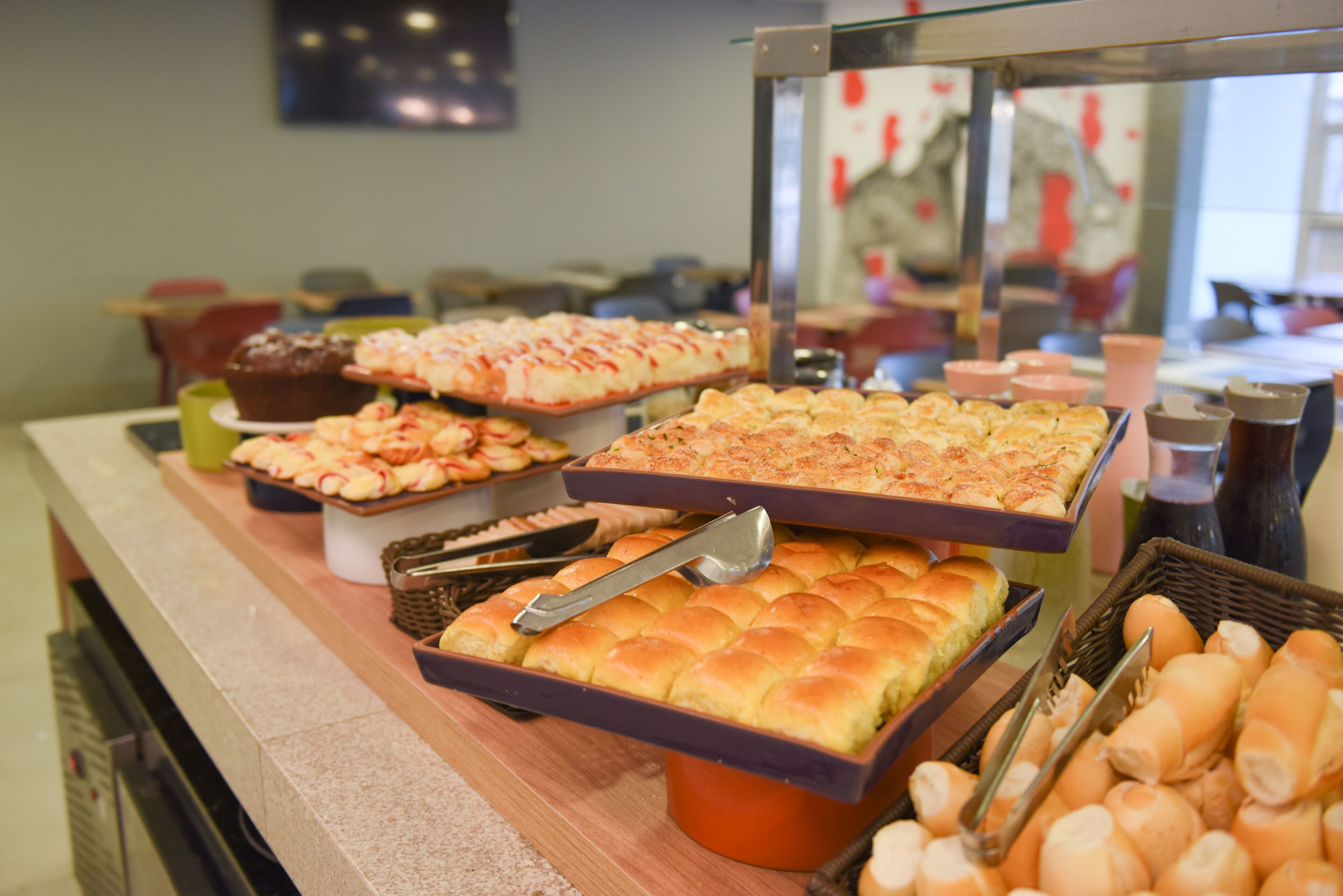 A buffet with various baked goods including bread, pastries, and rolls.