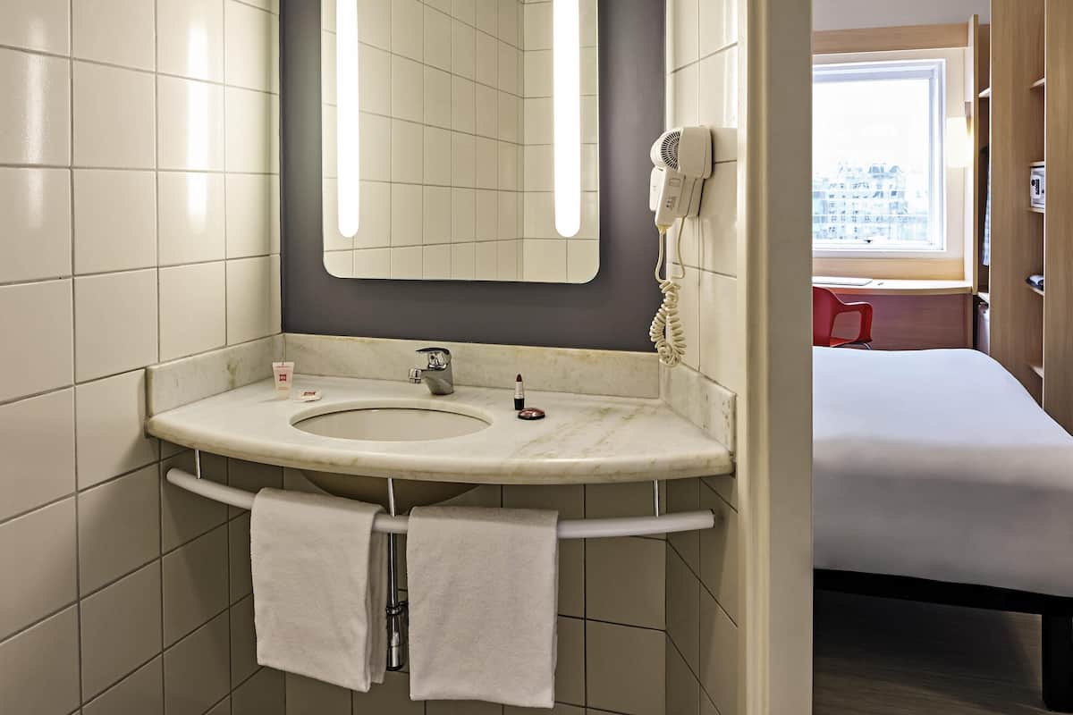 A bathroom with a sink, mirror, and towel rack.