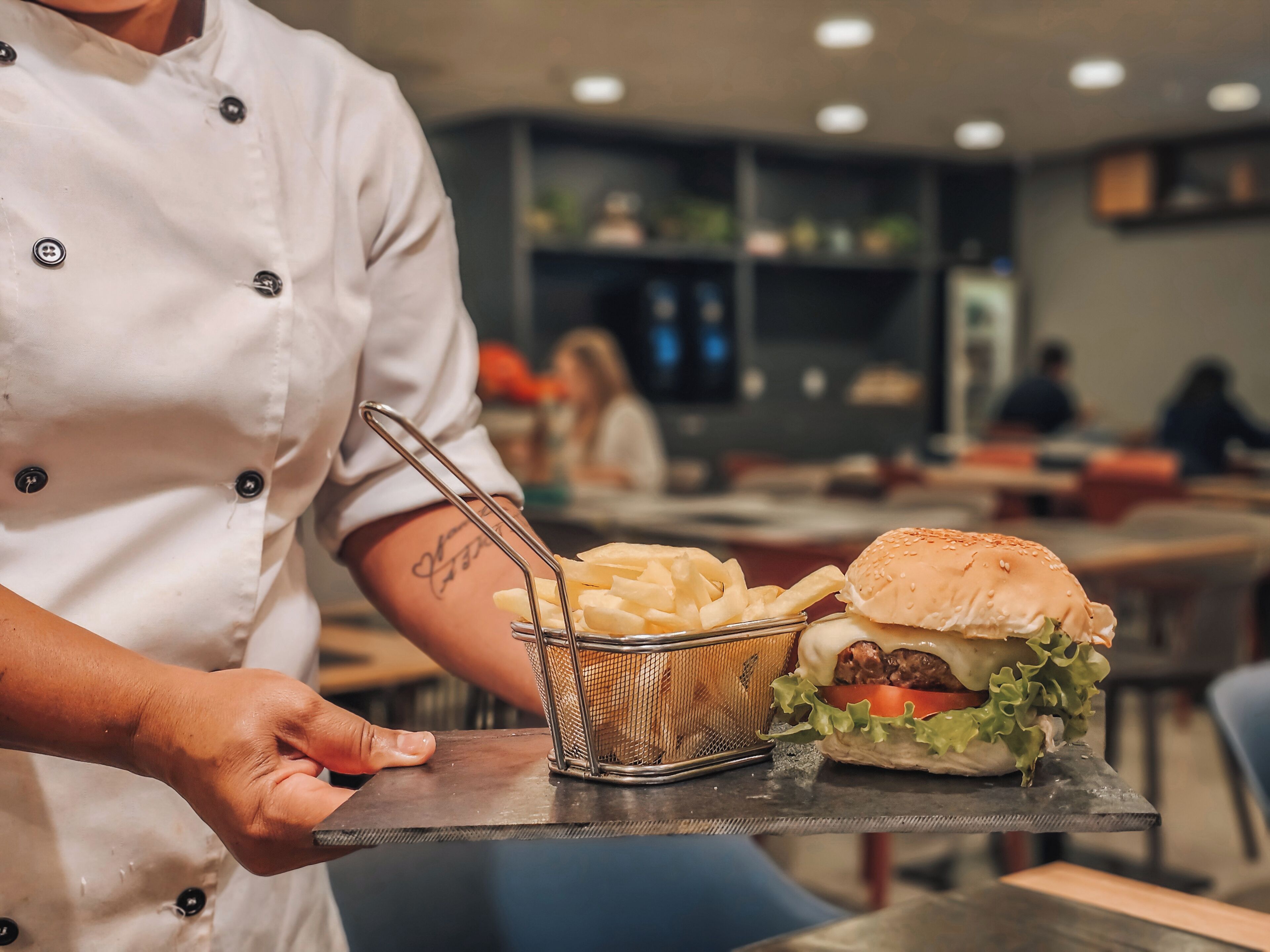 A chef holding a tray with a burger and fries.