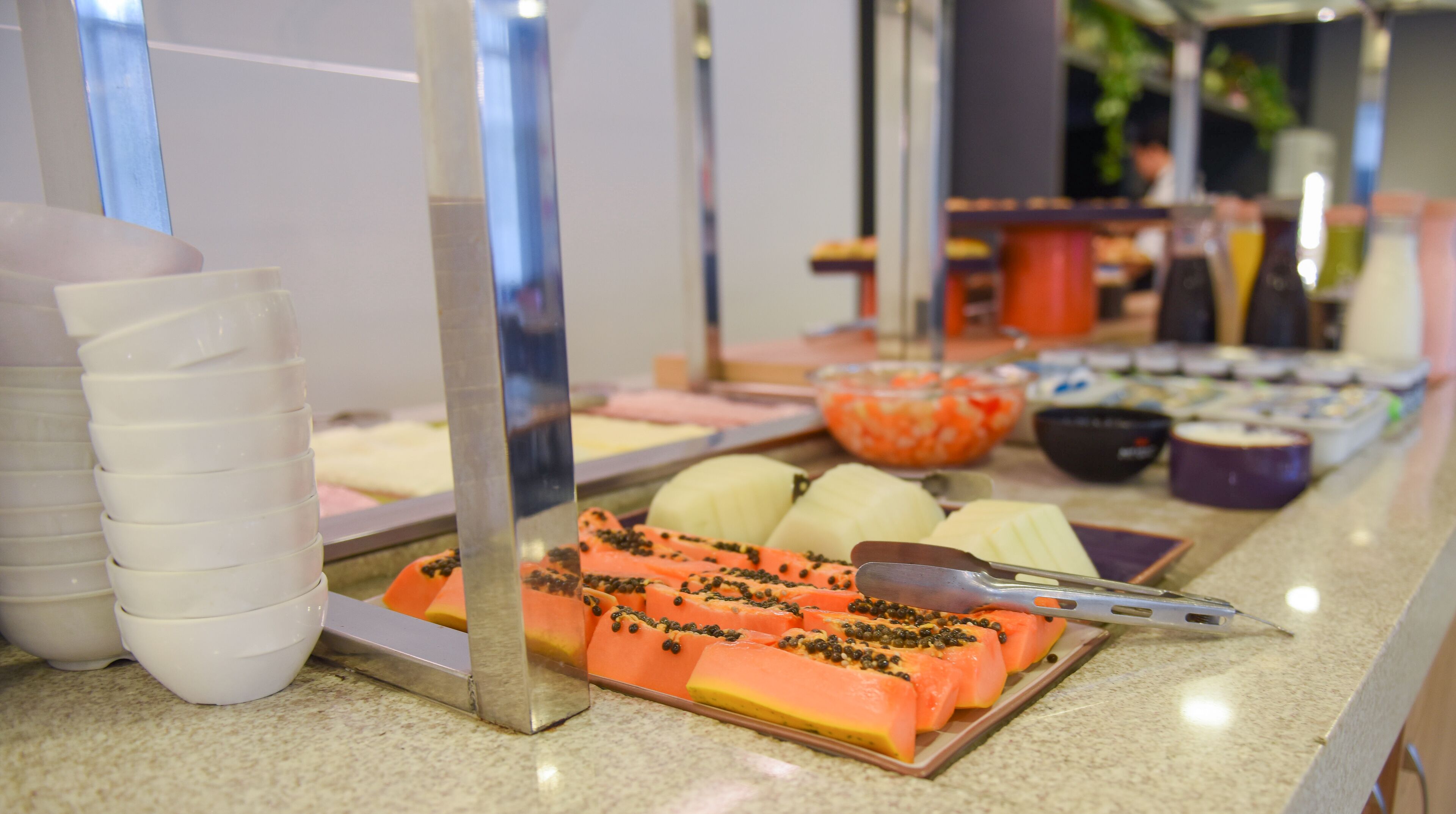 A buffet with various food items, including sliced fruits and vegetables, arranged on a counter.