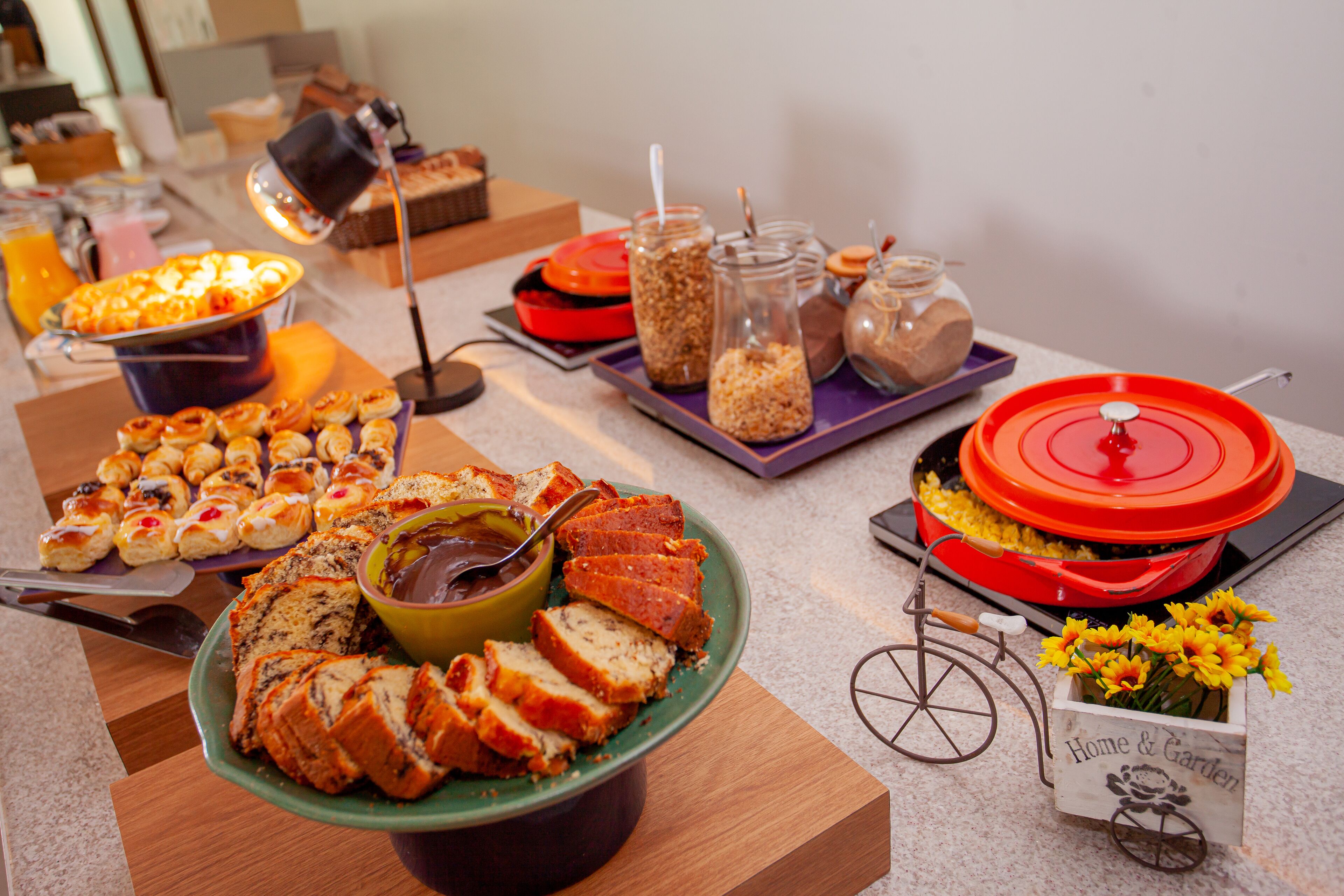 A buffet table with various food items, including pastries, bread, and a bowl of soup.