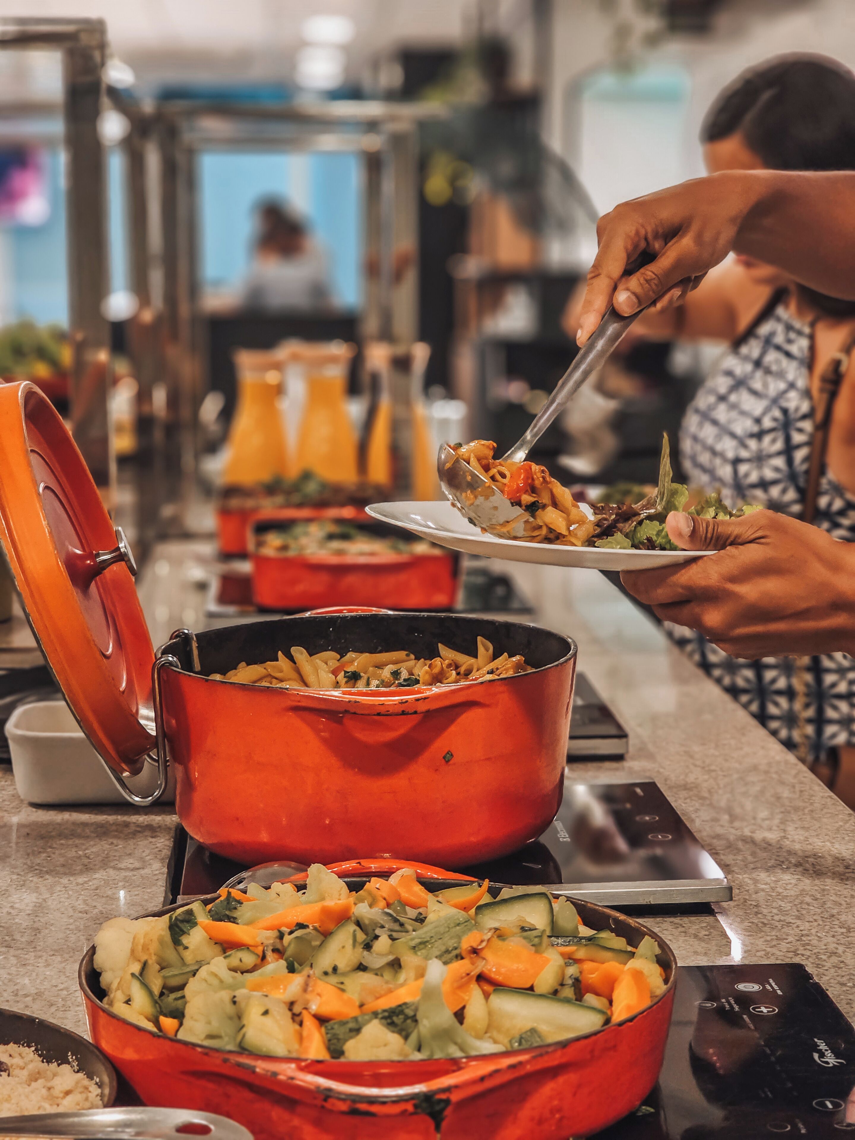 Un buffet proposant une variété de plats, notamment des pâtes et une salade de légumes, dans un espace intérieur bien éclairé.