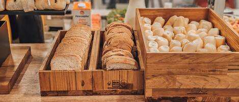 Una vitrina de panadería con varios tipos de pan, incluyendo pan integral y baguette, con etiquetas para facilitar la identificación.
