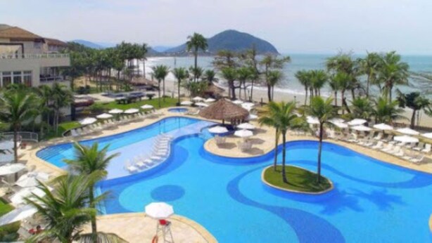A resort with a large swimming pool, beachside lounge areas, and a mountain in the background. - Hotel Jequitimar Guarujá Resort & Spa by Accor (Guarujá)