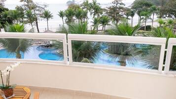 A balcony with a view of a pool and palm trees.