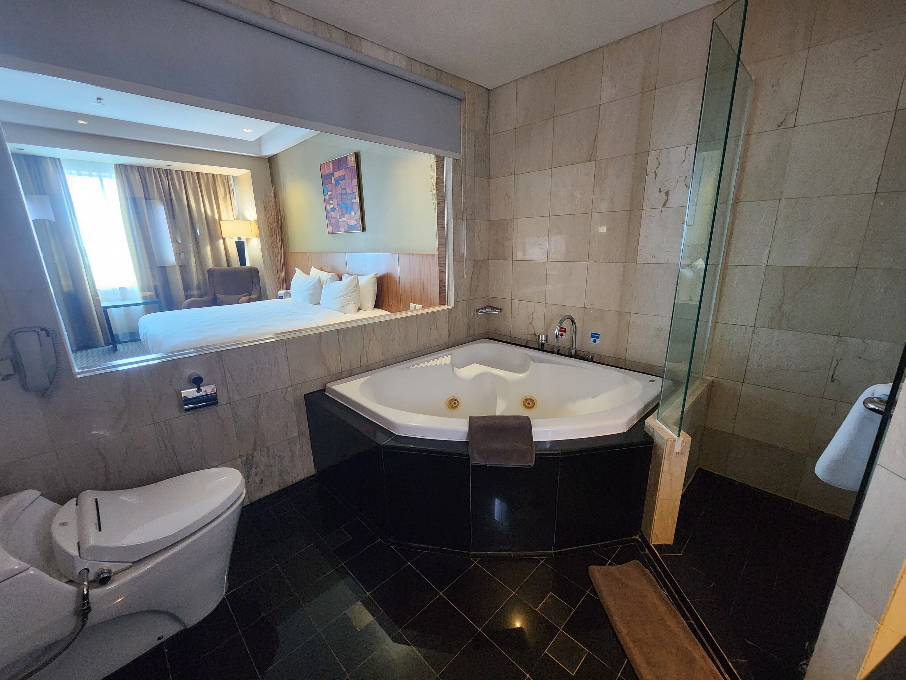 A modern bathroom with a large bathtub, a toilet, and a glass shower enclosure.