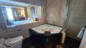 A modern bathroom with a large bathtub, a toilet, and a glass shower enclosure.