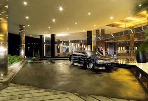 A modern hotel entrance with a black limousine parked in the driveway. - Novotel Balikpapan (Balikpapan)