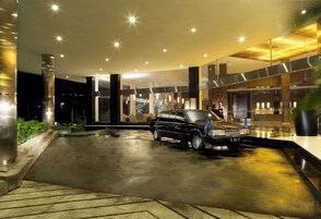 Una entrada de hotel moderna con una limusina negra estacionada en la entrada.