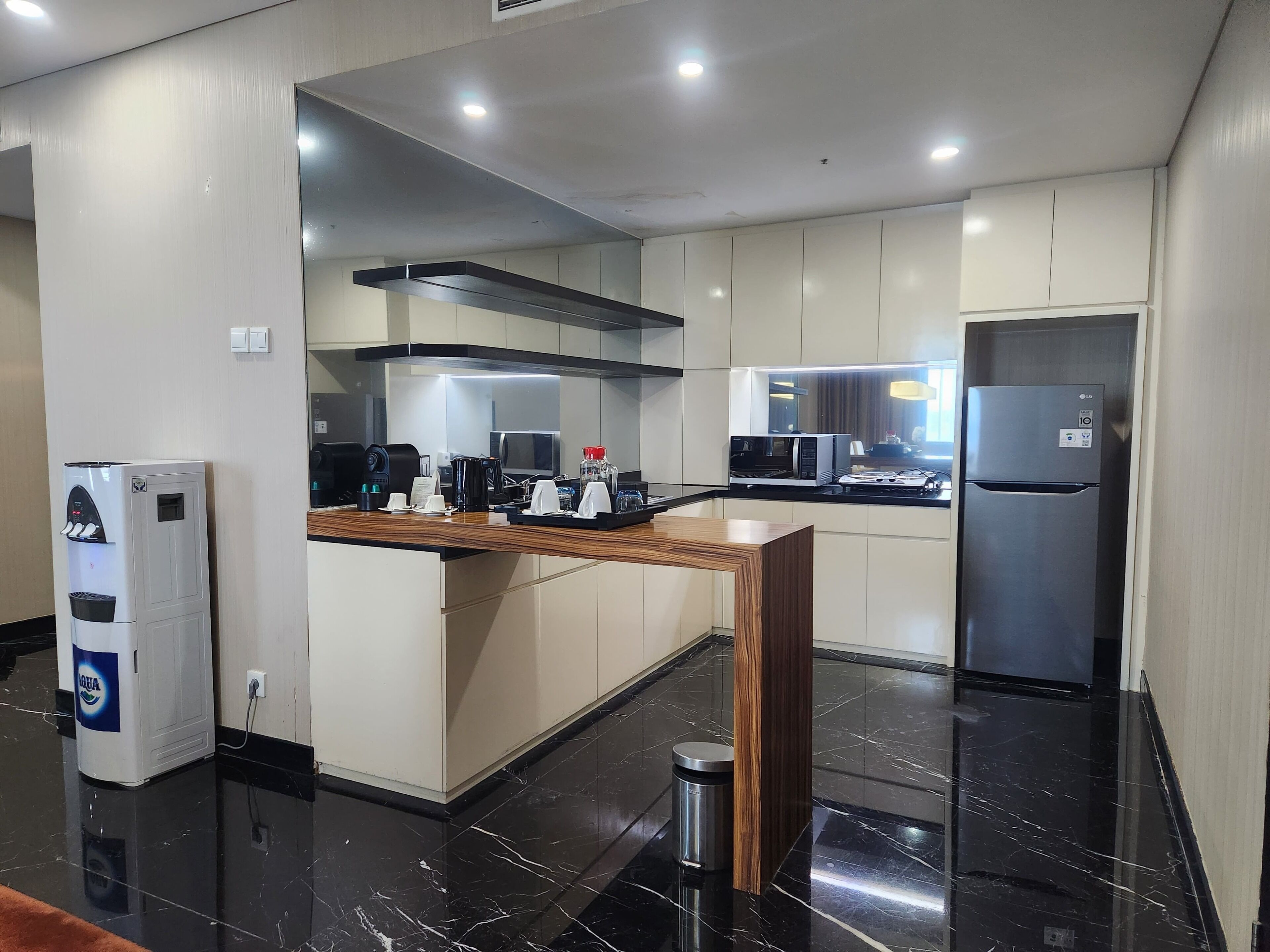 A modern kitchen with a built-in microwave, refrigerator, and coffee machine.