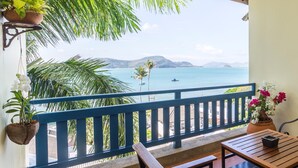 A balcony with a view of the sea, a wooden table, a bench, and potted plants. - Kantary Bay Hotel, Phuket (Wichit)