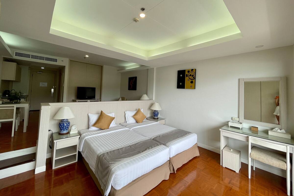 A hotel room with a large bed, bedside tables, a desk, and a mirror.