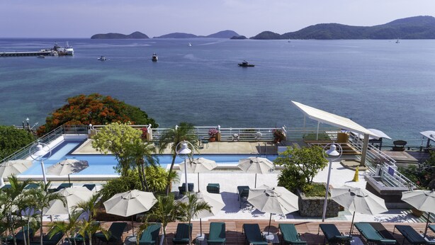 A rooftop pool area with lounge chairs and umbrellas, overlooking a calm sea with boats and distant islands. - Kantary Bay Hotel, Phuket (Wichit)