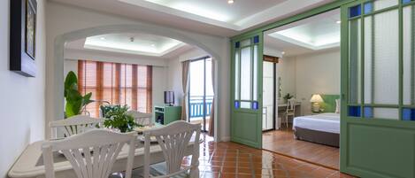 A hotel room with a dining area, a bed, and a bathroom.