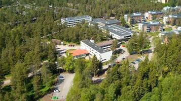 Vista aérea de un campus con varios edificios rodeados de un bosque denso.
