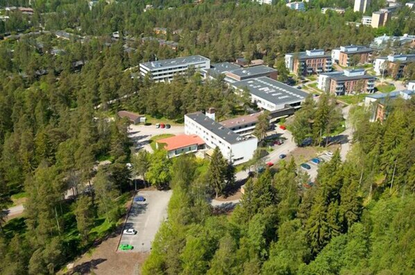 An aerial view of a campus with multiple buildings surrounded by dense forest. - Hotel Matinlahti (Espoo)