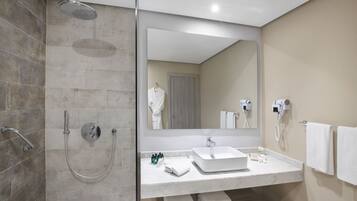 A modern bathroom with a walk-in shower, a large mirror, a sink, and a towel rack.