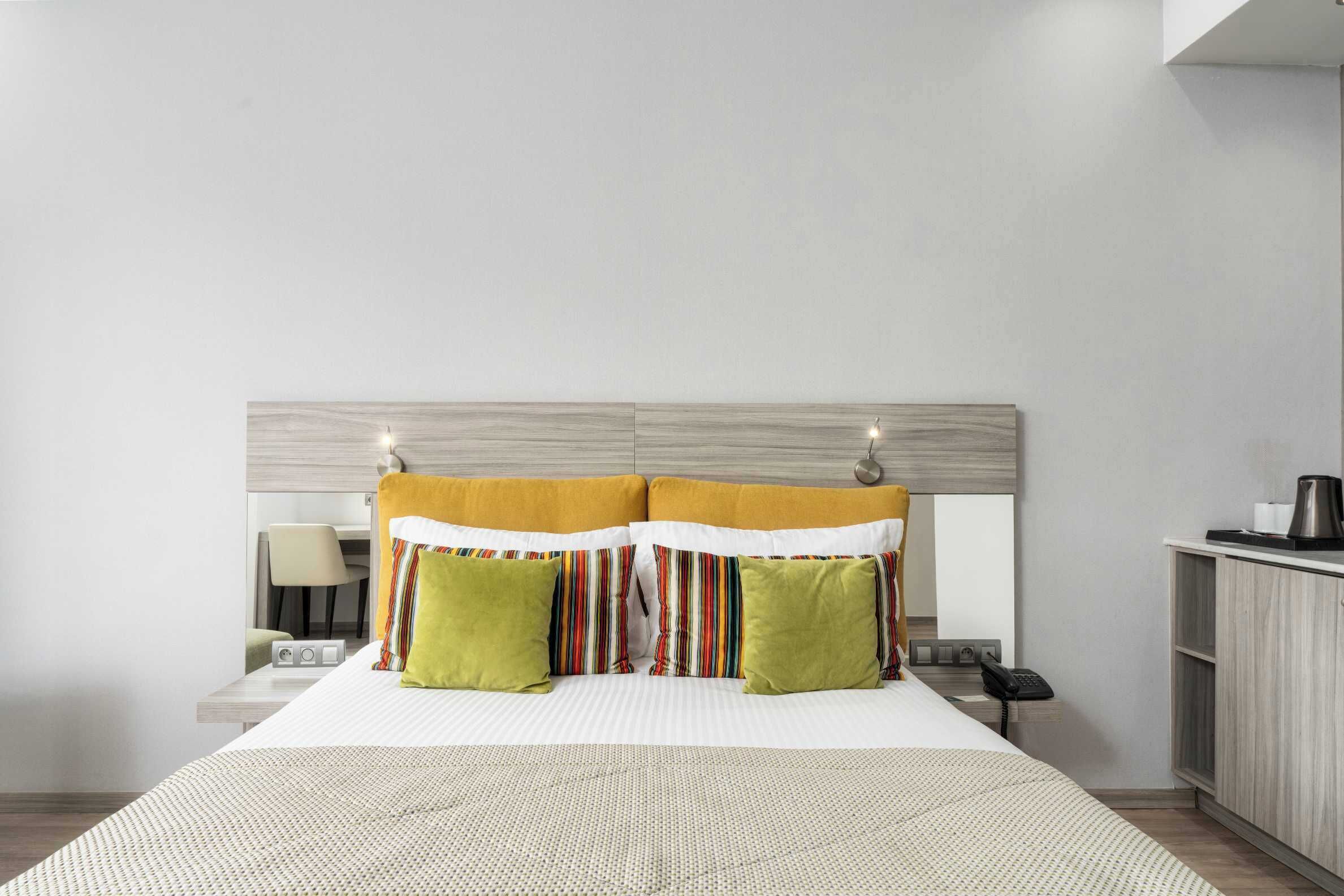 Una habitación de hotel con cama, mesita de noche, lámpara, teléfono y armario.