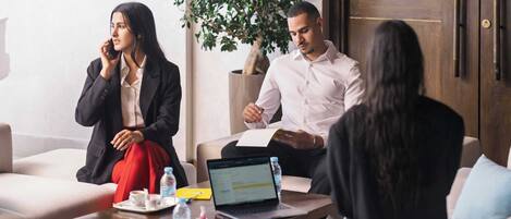 A meeting room with a laptop, documents, and a plant.