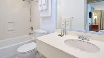 A bathroom with a bathtub, toilet, sink, and a large mirror.