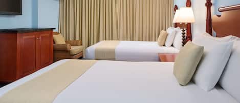A hotel room with two beds, a wooden headboard, a flat-screen TV, a desk, and a chair.