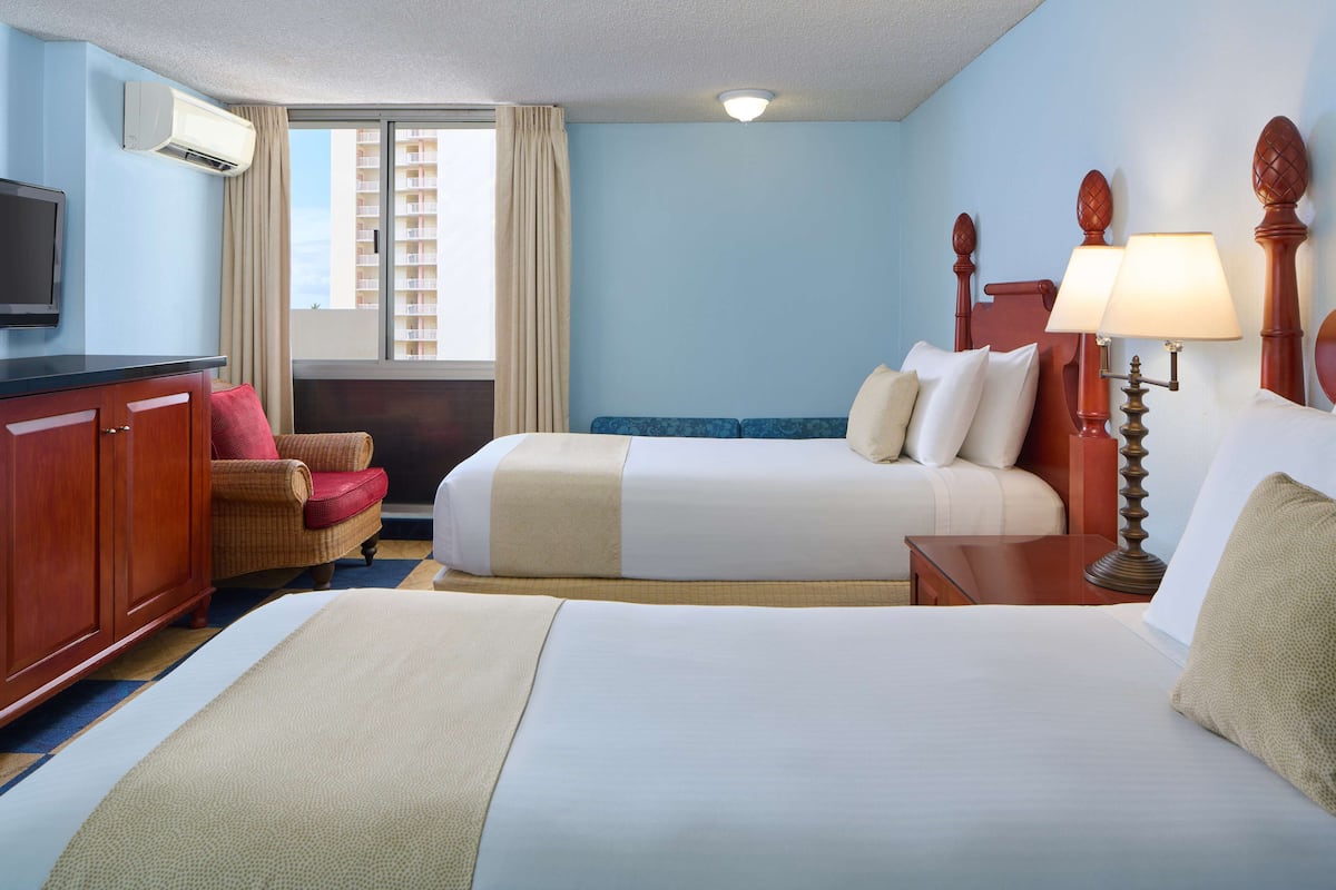 Une chambre d’hôtel avec deux lits, une télévision, un bureau et une chaise.