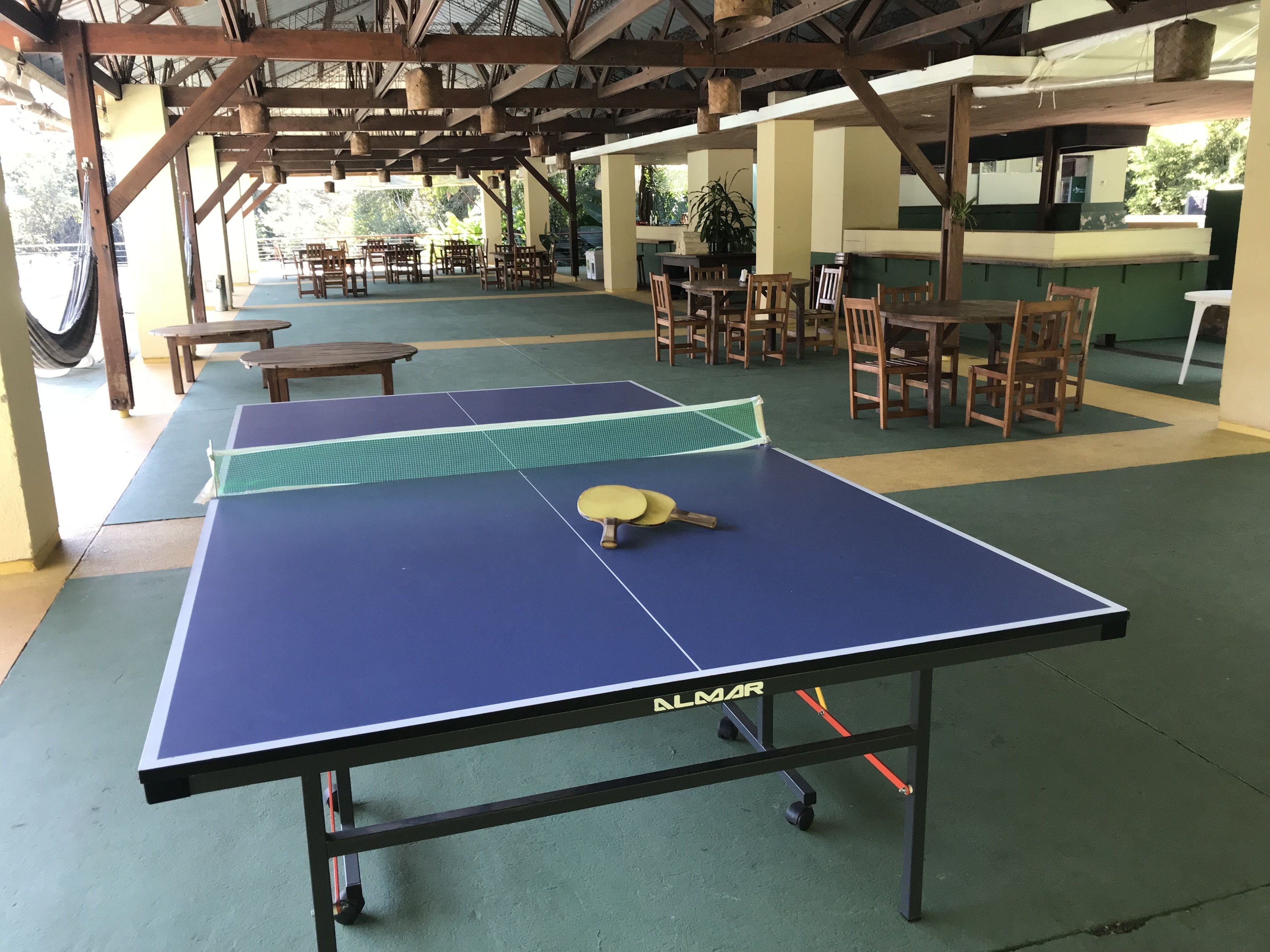 Una cancha de bádminton interior con una mesa de ping pong, sillas y una red.