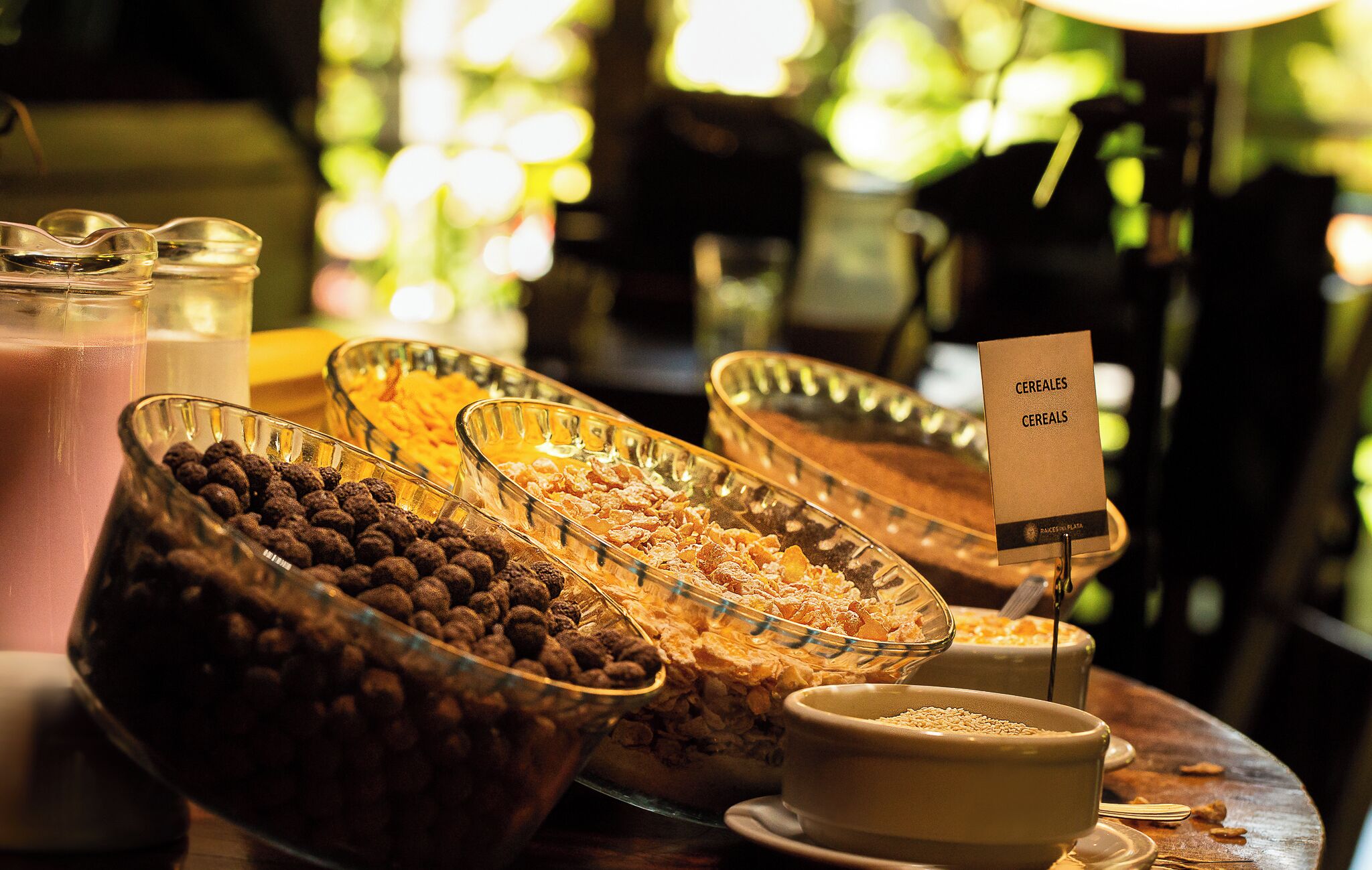 A buffet table with various food items including cereals, fruits, and beverages.