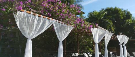 A covered outdoor seating area with white canopies and purple flowers.