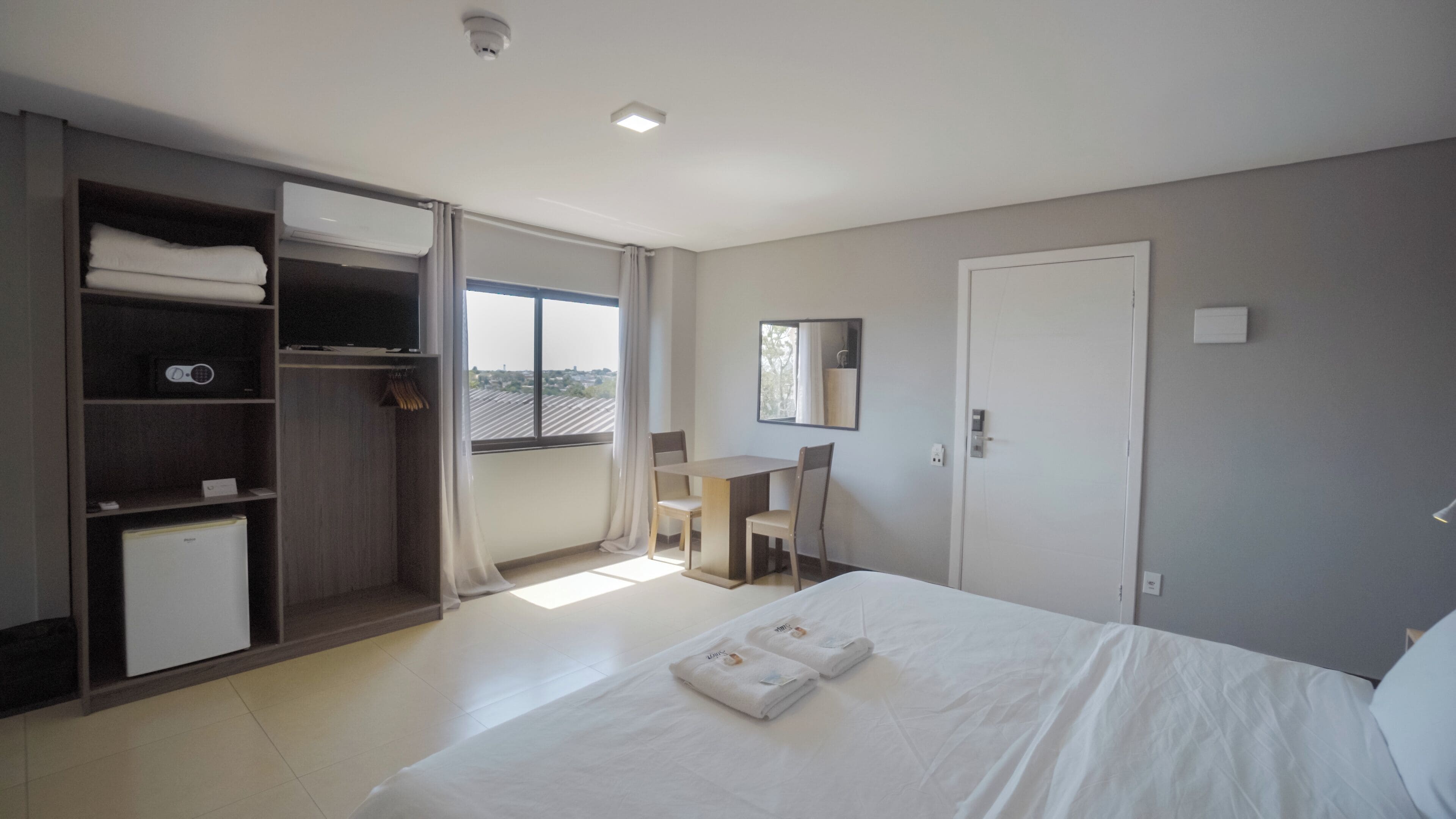 A bedroom with a bed, a desk, and a wardrobe.
