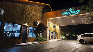 Das Hotel Suica Iguazu Resort & Hotel bei Nacht, mit einer Steinfassade, großen Fenstern und einem gut beleuchteten Eingang.