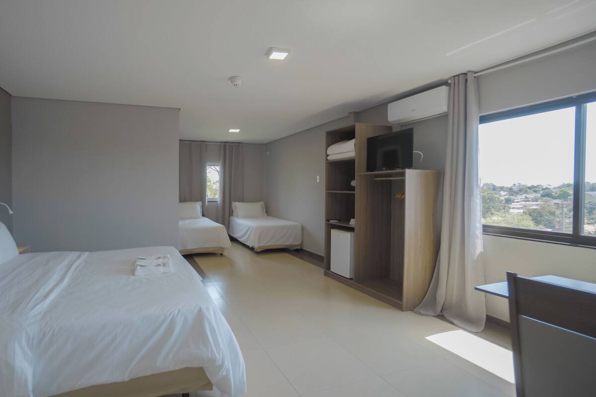 A hotel room with a large bed, a smaller bed, a wardrobe, and a desk.