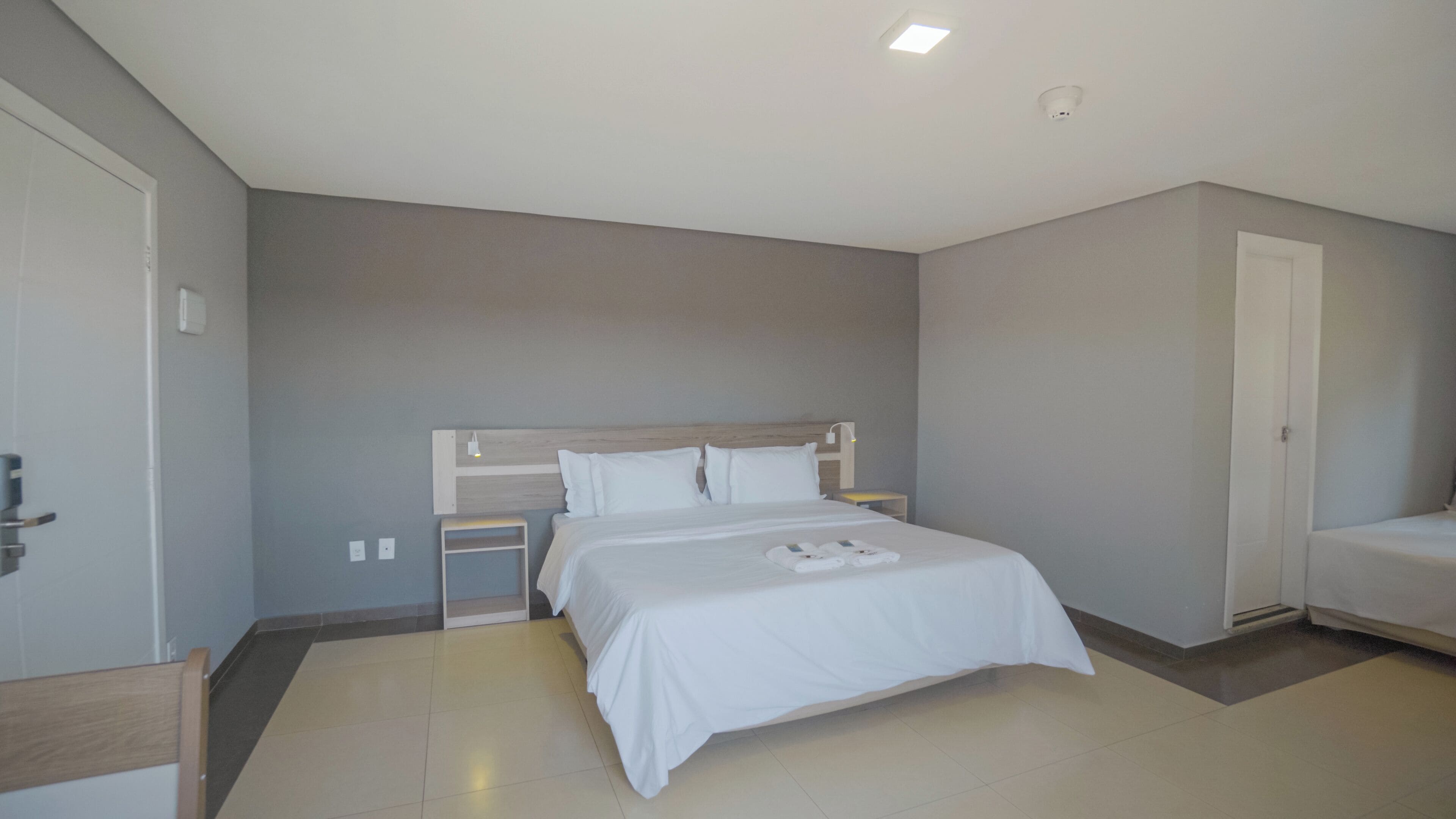 Ein modernes Hotelzimmer mit einem großen Bett, einem Nachttisch und einem Kleiderschrank.