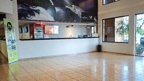 Eine großzügige Lobby mit einer großen Wandmalerei eines Wasserfalls, einem Empfangstresen und hängenden Korblampen.