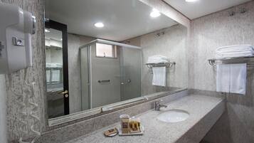 Un baño moderno con encimera de granito, un espejo grande, un lavabo y un perchero para toallas.