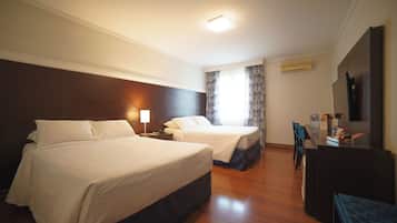 A hotel room with two beds, a desk, and a chair.