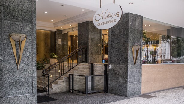A modern hotel entrance with a marble reception desk, a staircase, and a sign reading "Mabu Curitiba Business". - Mabu Curitiba Business (Curitiba)