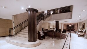 A spacious lobby with a grand staircase, a reception desk, and comfortable seating areas. - Mabu Curitiba Business (Curitiba)