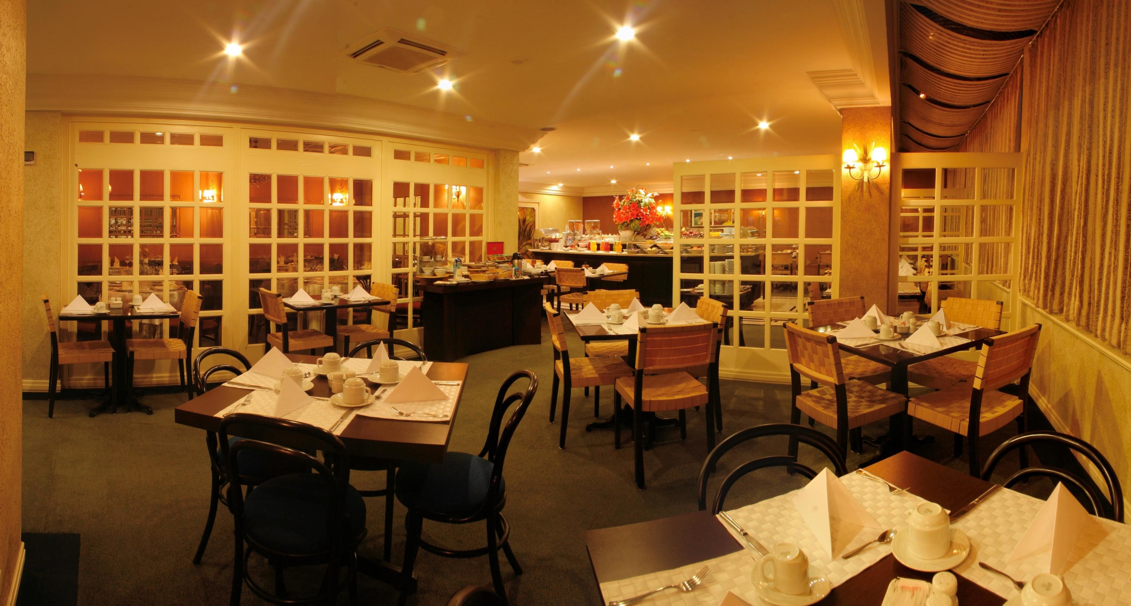 Un restaurante con varias mesas y sillas, una barra y un interior cálido y bien iluminado.