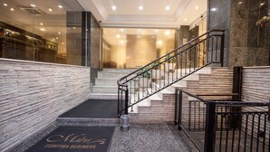 A hotel lobby with a marble staircase, a reception desk, and a doormat with the hotel's name. - Mabu Curitiba Business (Curitiba)