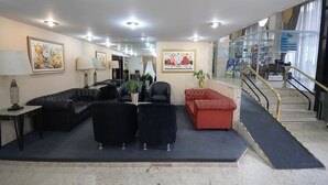 A lobby with a seating area, a staircase, and a reception desk. - Caravelle Palace Hotel (Curitiba)