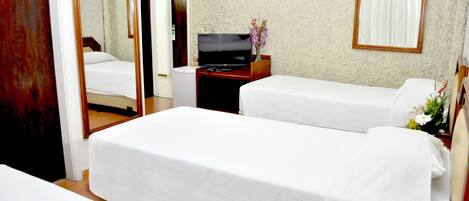 A hotel room with two single beds, a TV, a small desk, and a mirror.