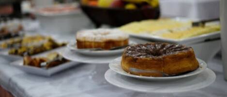 Una mesa de buffet con diversos postres y un frutero al fondo.